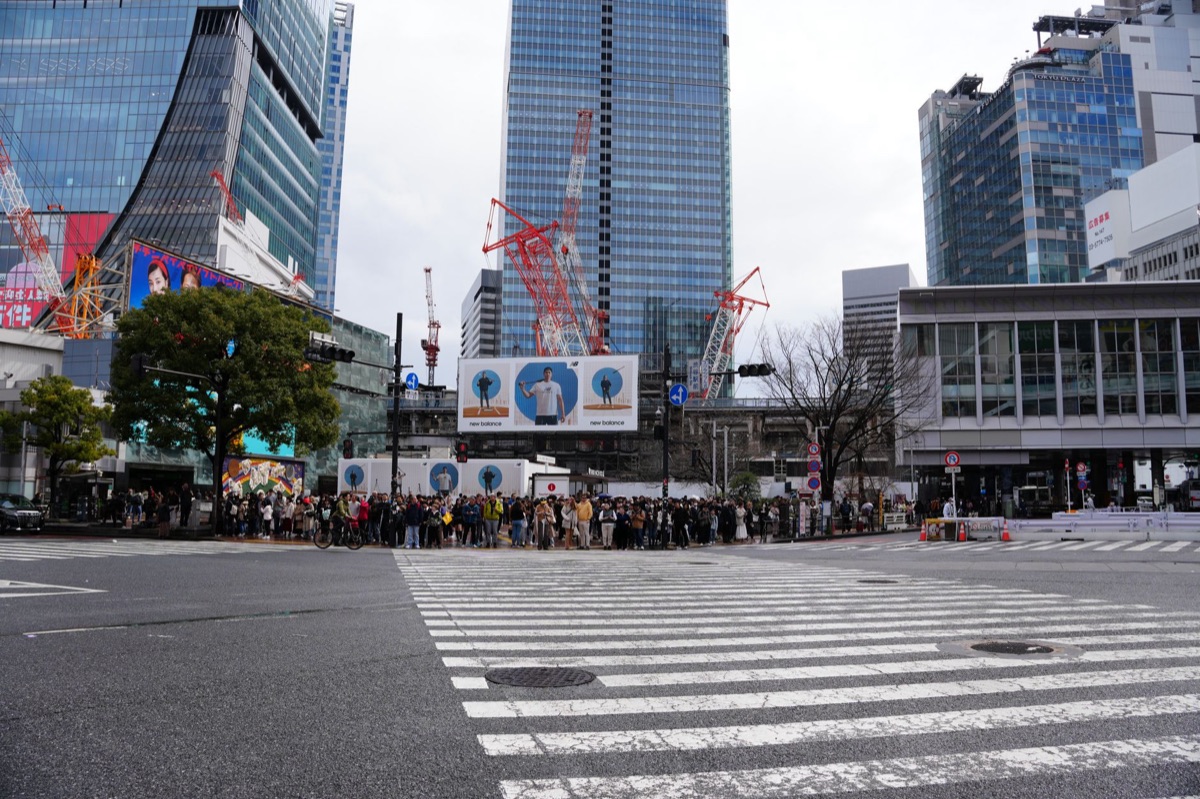 Rue de Shibuya à Tokyo, montrant des passants sous un ciel gris et nuageux