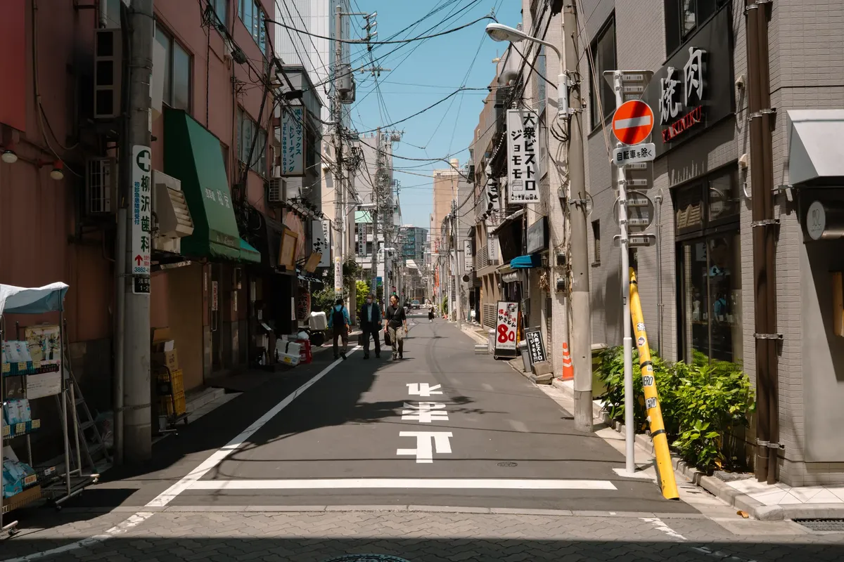 静かな東京の通り。晴れた日の都会の生活と伝統的な建築が紹介されている。