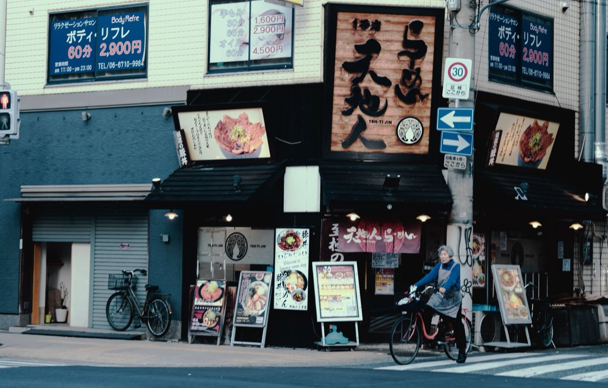 A vintage sign outside a Tokyo restaurant with calligraphy and a red lantern