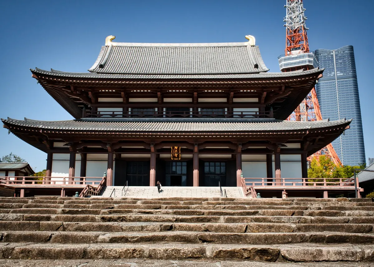 Beautiful view of Zojoji Temple with Tokyo Tower in the background under clear blue skies.